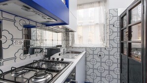 A kitchen with a gas stove, a sink, and a window with a floral pattern. - Ripetta Deluxe Terrace (Rome)