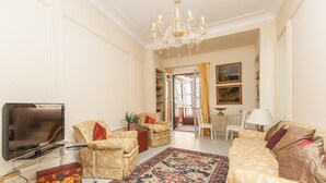 A living room with a TV, sofas, a chandelier, and a patterned rug. - Ripetta Deluxe Terrace (Rome)