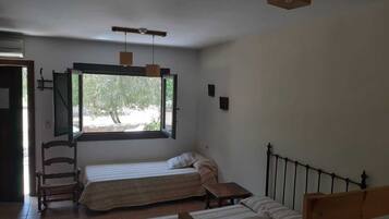 Een slaapkamer met twee bedden, een raam en een stoel.