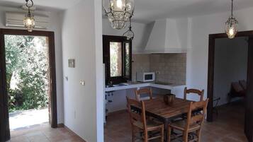A kitchen with a dining table and chairs, a microwave, and a window overlooking greenery.