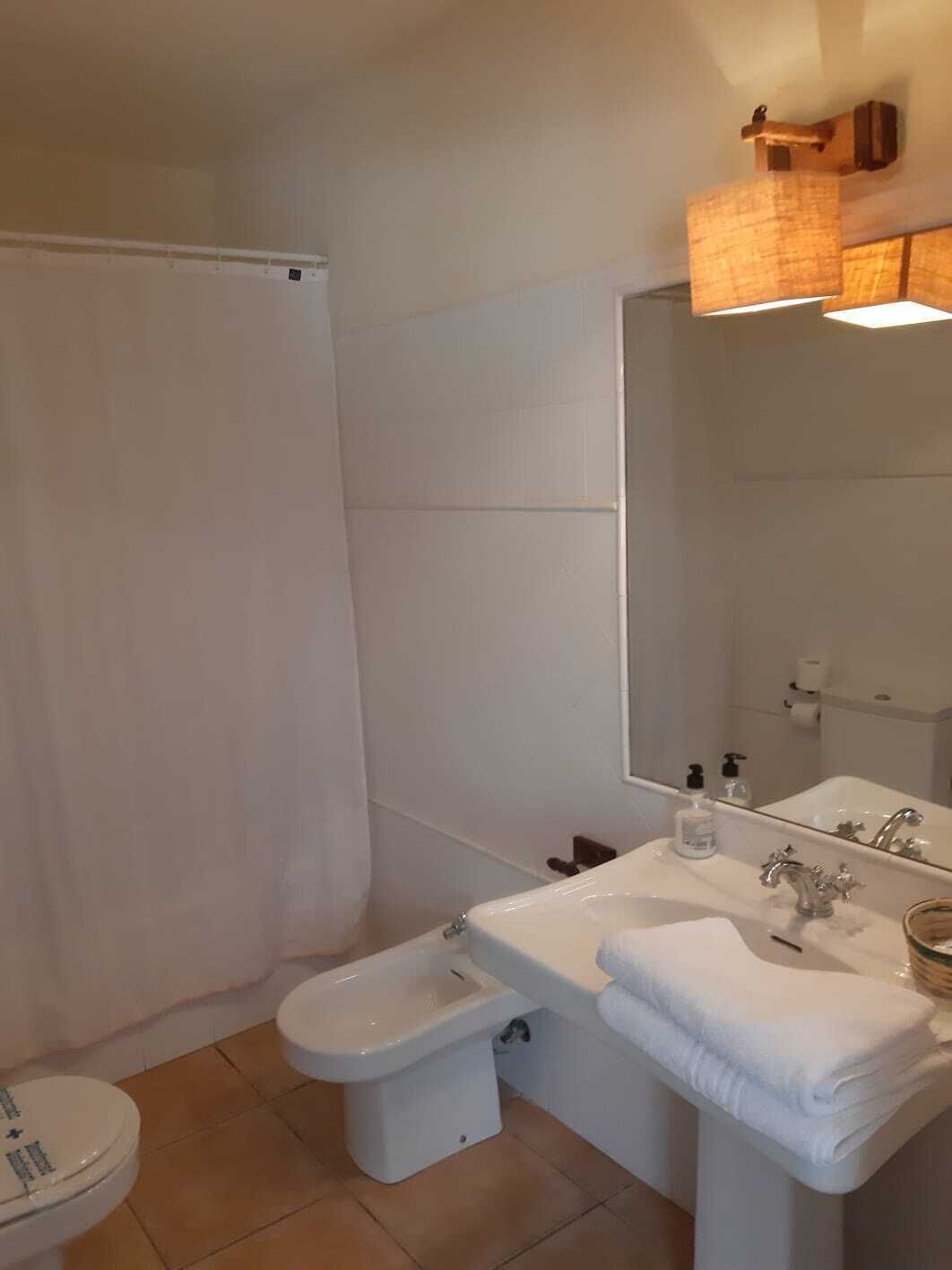 Un baño con inodoro, bidé, lavabo y espejo.