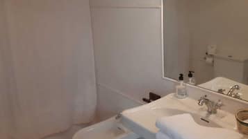 Un baño con inodoro, bidé, lavabo y espejo.