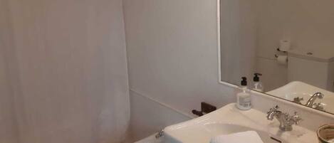 Un baño con inodoro, bidé, lavabo y espejo.