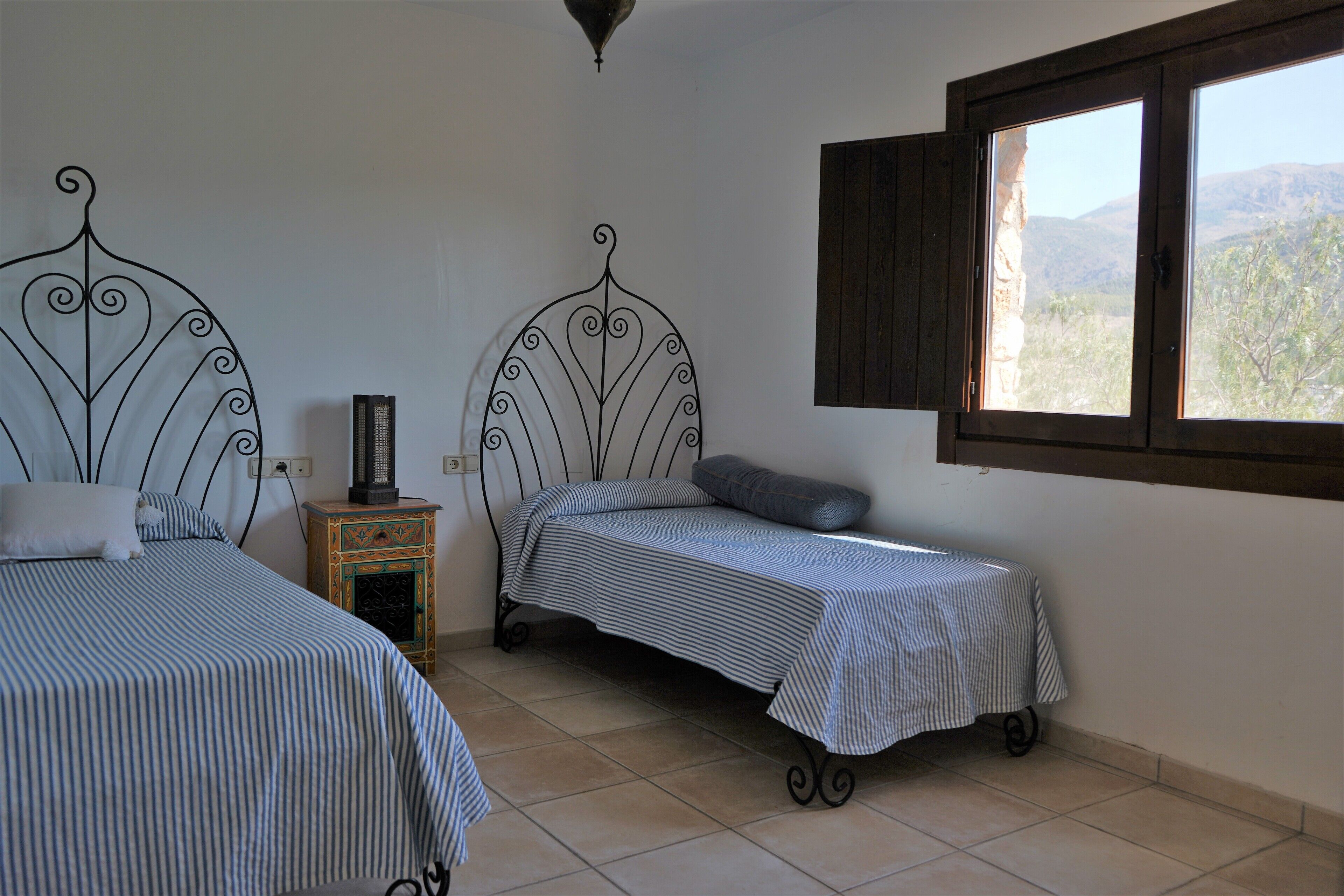 Un dormitorio con dos camas, un calentador y una ventana con vistas a las colinas.