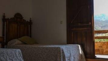 Una habitación con una cama, una mesita y una puerta grande de madera que da a un balcón.