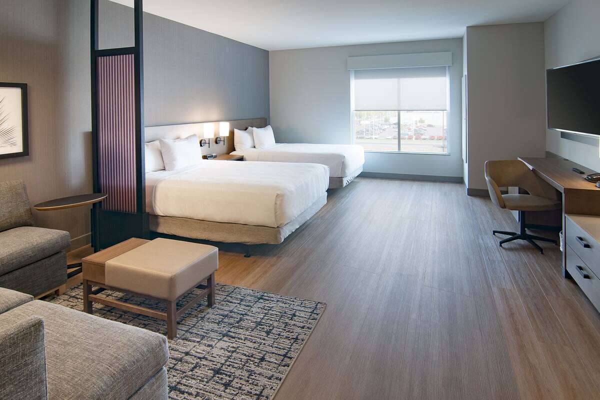 Une chambre d’hôtel moderne équipée de deux lits, d’un bureau, d’une chaise et d’un téléviseur.
