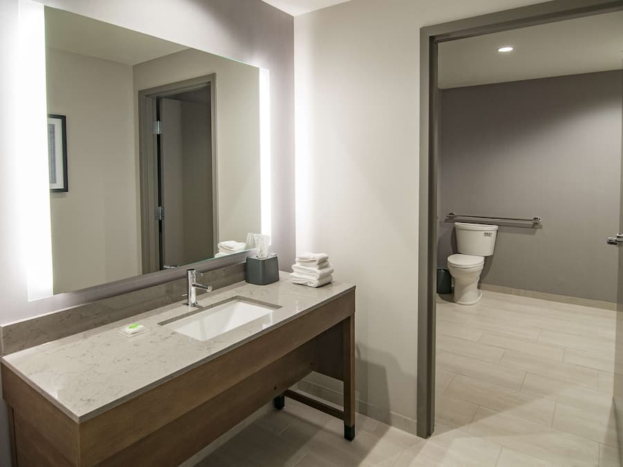 A modern bathroom with a large mirror, a sink, and a toilet.