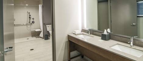 A modern bathroom with two sinks, a shower, and a toilet.