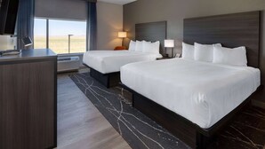 Quarto de hotel com duas camas, uma escrivaninha e uma janela grande com vista para o deserto.
