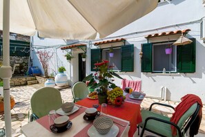 Enjoy al fresco dining in a shaded outdoor space with a beautifully set table and comfortable seating.