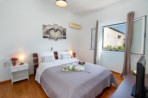 Relax in comfort with a large bed, flat-screen TV, and a potted plant.