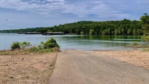 A paved path leading to a lake with a dock in the distance and a forested hill.