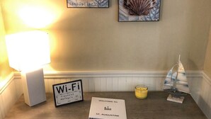 Una taulell de recepció amb un cartell de Wi-Fi, un cartell de benvinguda, una espelma i una petita decoració de veler.
