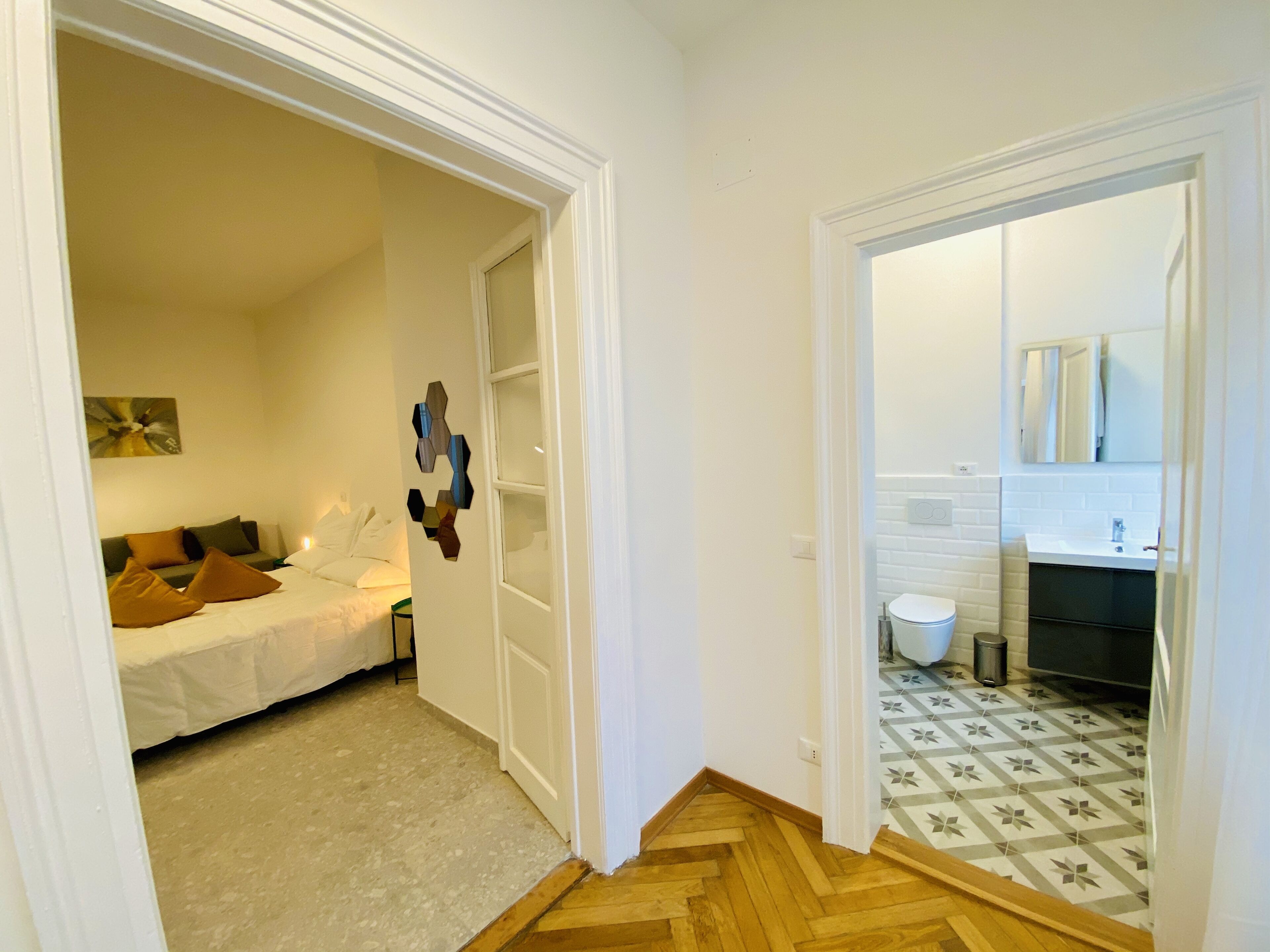 Une chambre comprenant un lit, une œuvre d’art accrochée au mur, et une salle de bain carrelée avec un lavabo.