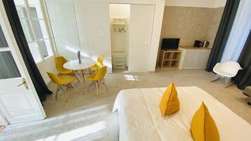 Habitación de hotel con cama, escritorio, silla, televisor y armario.