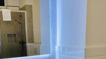 A bathroom with a white sink, a mirror, and a shower area.