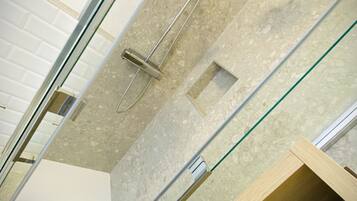 A modern bathroom with a glass shower enclosure, a built-in toilet, and a wooden vanity with a towel.