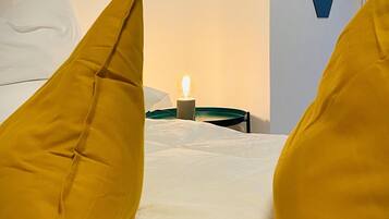 A hotel room with a bed, yellow pillows, a bedside table with a lamp, and a wall with a geometric pattern.