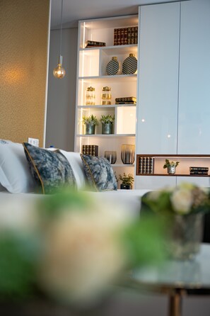 Una sala de estar moderna con un sofá, un lámpara colgante y una estantería empotrada decorada con objetos.