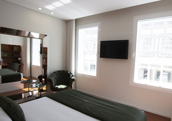 Habitación de hotel con cama, una silla, un escritorio, un espejo y un televisor.