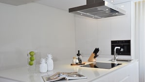Una cocina moderna con armarios blancos, una isla central, horno empotrado y una campana extractora de acero inoxidable.