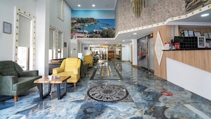 A hotel lobby with a marble floor, a reception desk, and a seating area with chairs. - Piyes Otel (Antalya)