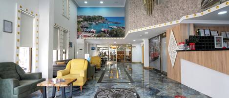 A hotel lobby with a marble floor, a reception desk, and a seating area with chairs.