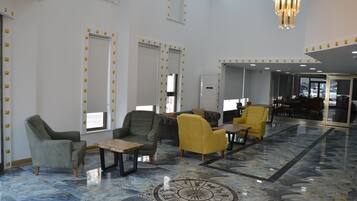 Um hall amplo com piso de mármore, várias áreas de estar e um candelabro.