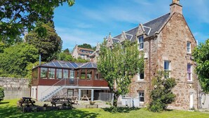 A stone building with a glass conservatory and a wooden deck.