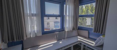 A room with a bench seat, a table, and a window with curtains.