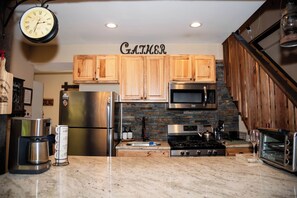 A kitchen with wooden cabinets, stainless steel appliances, a clock, and a sign that reads 'GAMBR.'