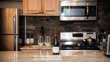 A kitchen with wooden cabinets, a stainless steel refrigerator, a microwave, and a stove.