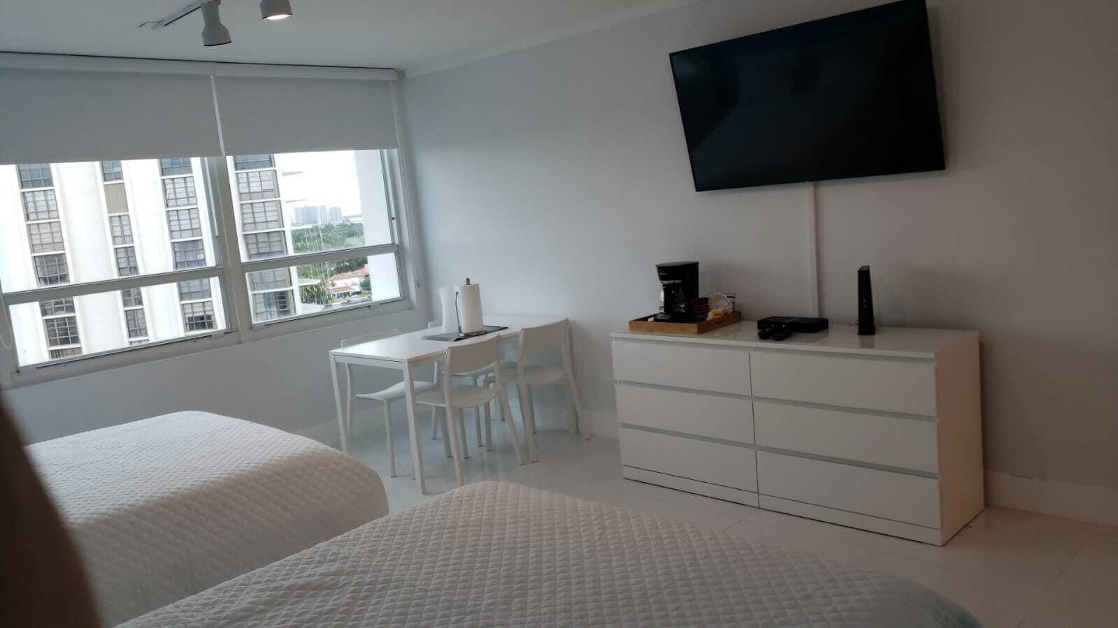 A hotel room with two beds, a desk, a chair, a TV, and a dresser.