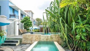 Un espace piscine offrant une vue dégagée sur le bassin, des marches menant à la piscine et un bâtiment doté d’un balcon.