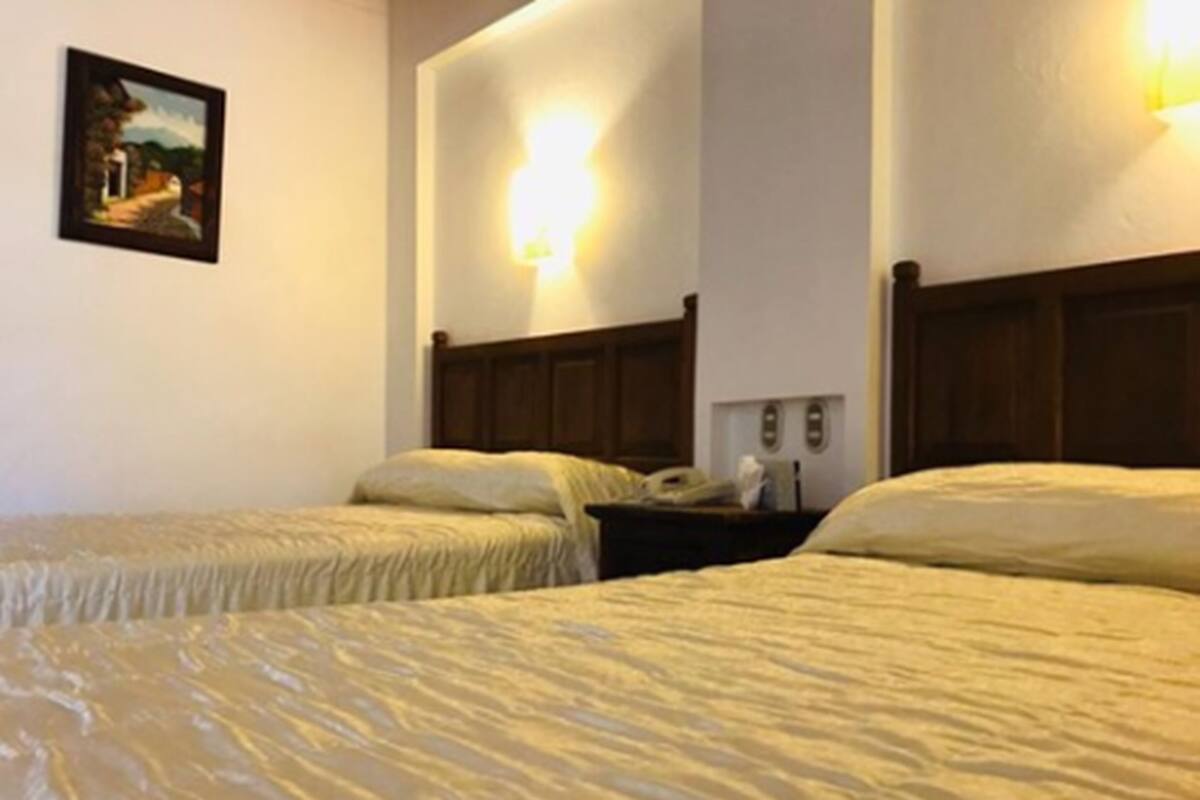 Ein Hotelzimmer mit zwei Betten, einem Bild an der Wand und einem Nachttisch mit Lampe.