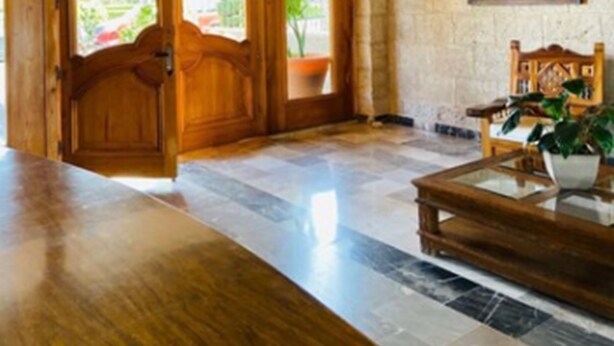 A spacious lobby with a high, vaulted ceiling and a large wooden reception desk. - Hotel La Mansión (San José Iturbide)