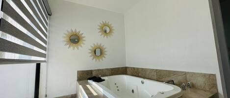 A modern bathroom with a freestanding bathtub, marble countertops, and decorative sunburst mirrors on the wall.
