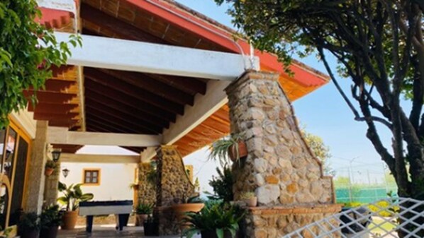 A building with a stone pillar, a wooden roof, and potted plants. - Hotel La Mansión (San José Iturbide)