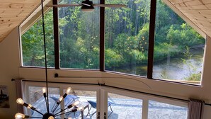 Una habitación con ventanas amplias que dan a un bosque y un río.