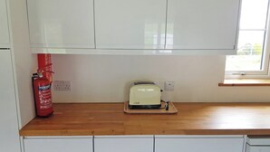 A kitchen with white cabinets, a wooden countertop, a toaster, and a fire extinguisher. - 1 bedroom accommodation in Rosemarkie (Rosemarkie)
