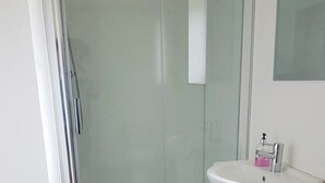 A bathroom with a shower, a sink, and a mirror. - 1 bedroom accommodation in Rosemarkie (Rosemarkie)