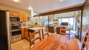 A modern kitchen with wooden cabinets, stainless steel appliances, and a wooden dining table. - Ski-In/Ski-Out, Hot Tub, Fireplace & Mountain Views (Crested Butte)
