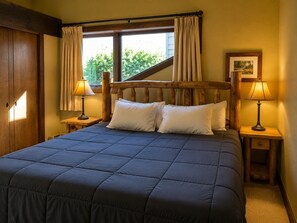 A bedroom with a large bed, two bedside tables with lamps, a wooden headboard, and a window with curtains. - Ski-In/Ski-Out, Hot Tub, Fireplace & Mountain Views (Crested Butte)