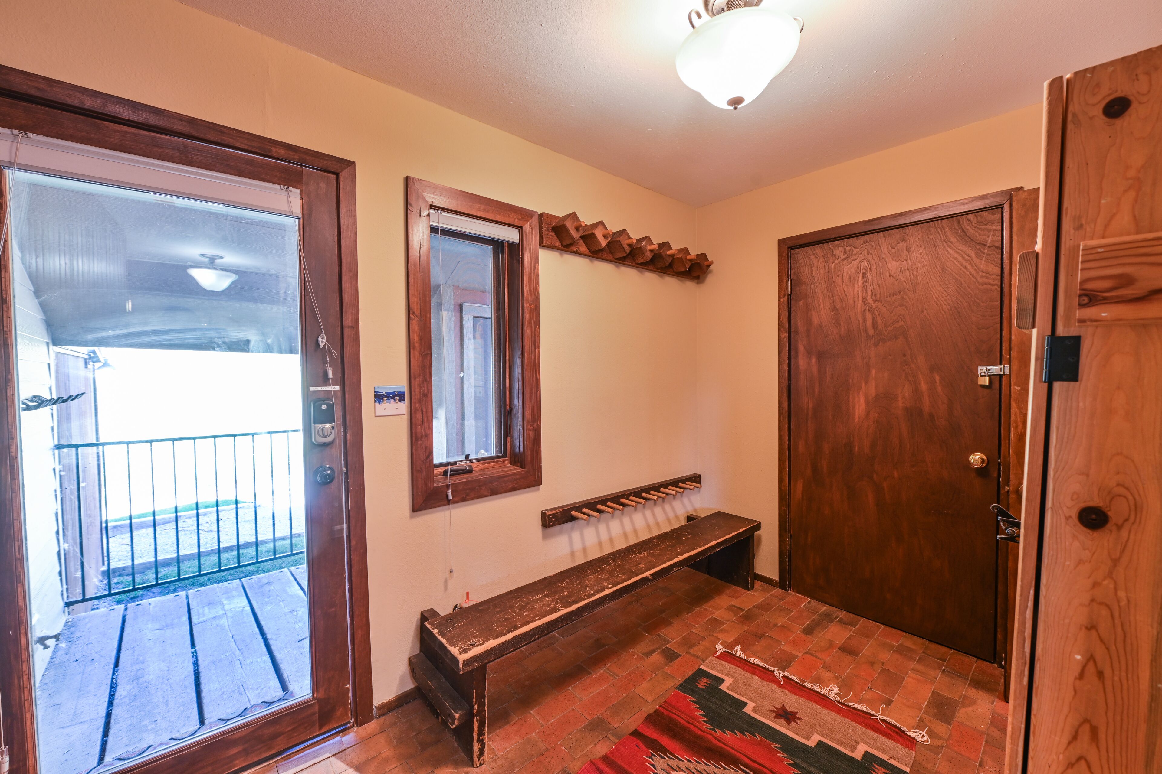 A room with a wooden bench, a door, a window, and a light fixture.