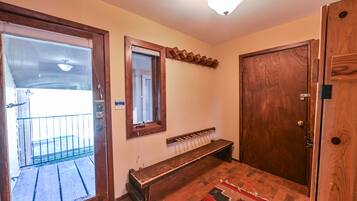 A room with a wooden bench, a door, a window, and a light fixture.