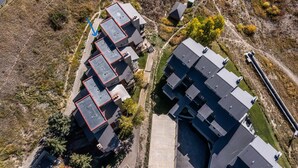 An aerial view of a residential area with multiple buildings, including a large complex with a central courtyard and smaller structures around it. - Ski-In/Ski-Out, Hot Tub, Fireplace & Mountain Views (Crested Butte)