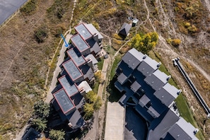 An aerial view of a residential area with multiple buildings, including a large complex with a central courtyard and smaller structures around it. - Ski-In/Ski-Out, Hot Tub, Fireplace & Mountain Views (Crested Butte)