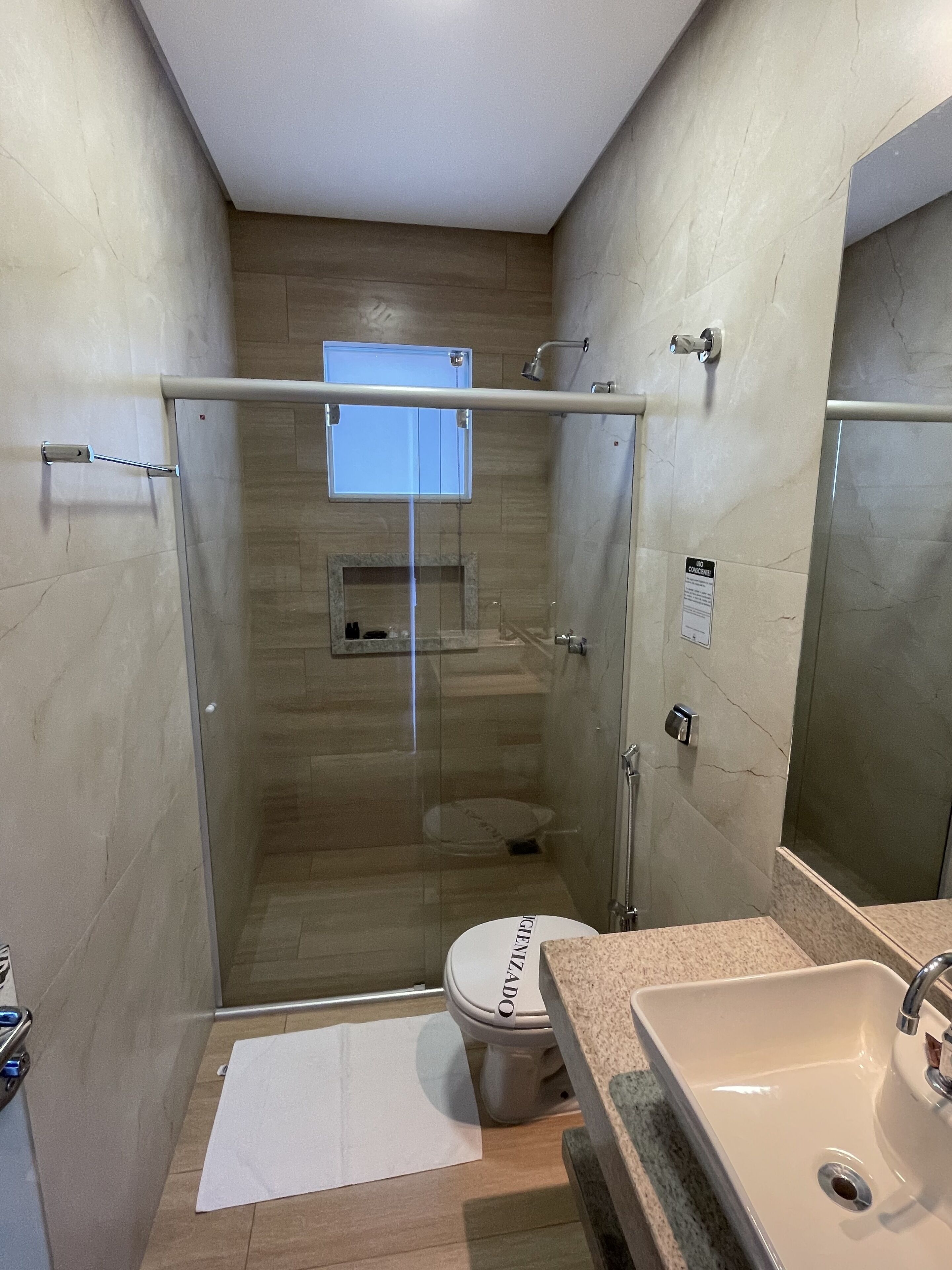 Casa de banho compacta com cabine de duche em vidro, sanita e lavatório.