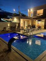 Una piscina al aire libre, sillones reclinables de piscina