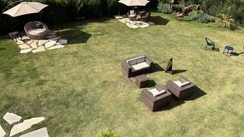 A well-maintained outdoor patio area with wicker furniture, stone pathways, and lush greenery.